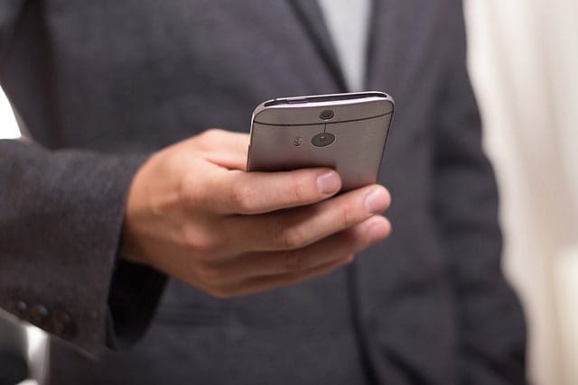 Man in suit dialing a cell phone, symbolizing the immediate legal assistance available at Hansen & Harmon Injury Law - personal injury law firm