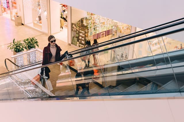 Woman with shopping bags using an escalator, denoting the everyday scenarios where premises liability issues arise... handled by Hansen & Harmon Injury Law