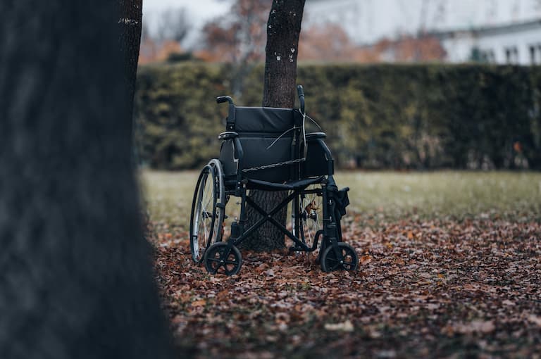 Abandoned wheelchair chained against a tree